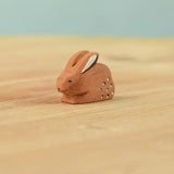 The Bumbu Toys wooden baby brown rabbit, sat in a perching position