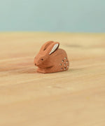 The Bumbu Toys wooden baby brown rabbit, sat in a perching position
