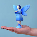 The Bumbu water fairy balanced on an adult's hand against a blue background.