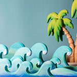 Bumbu waves wooden toys pictured with palm trees in the background.