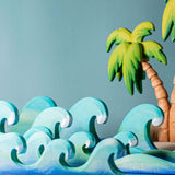 Bumbu waves wooden toys pictured with palm trees in the background.