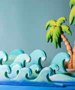Bumbu waves wooden toys pictured with palm trees in the background.