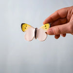Bumbu Toys Wooden Butterfly in Yellow, being held in an adult's hand.