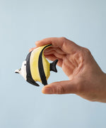 A Bumbu Toys Moorish Idol Fish being held in an adult's hand to show scale.