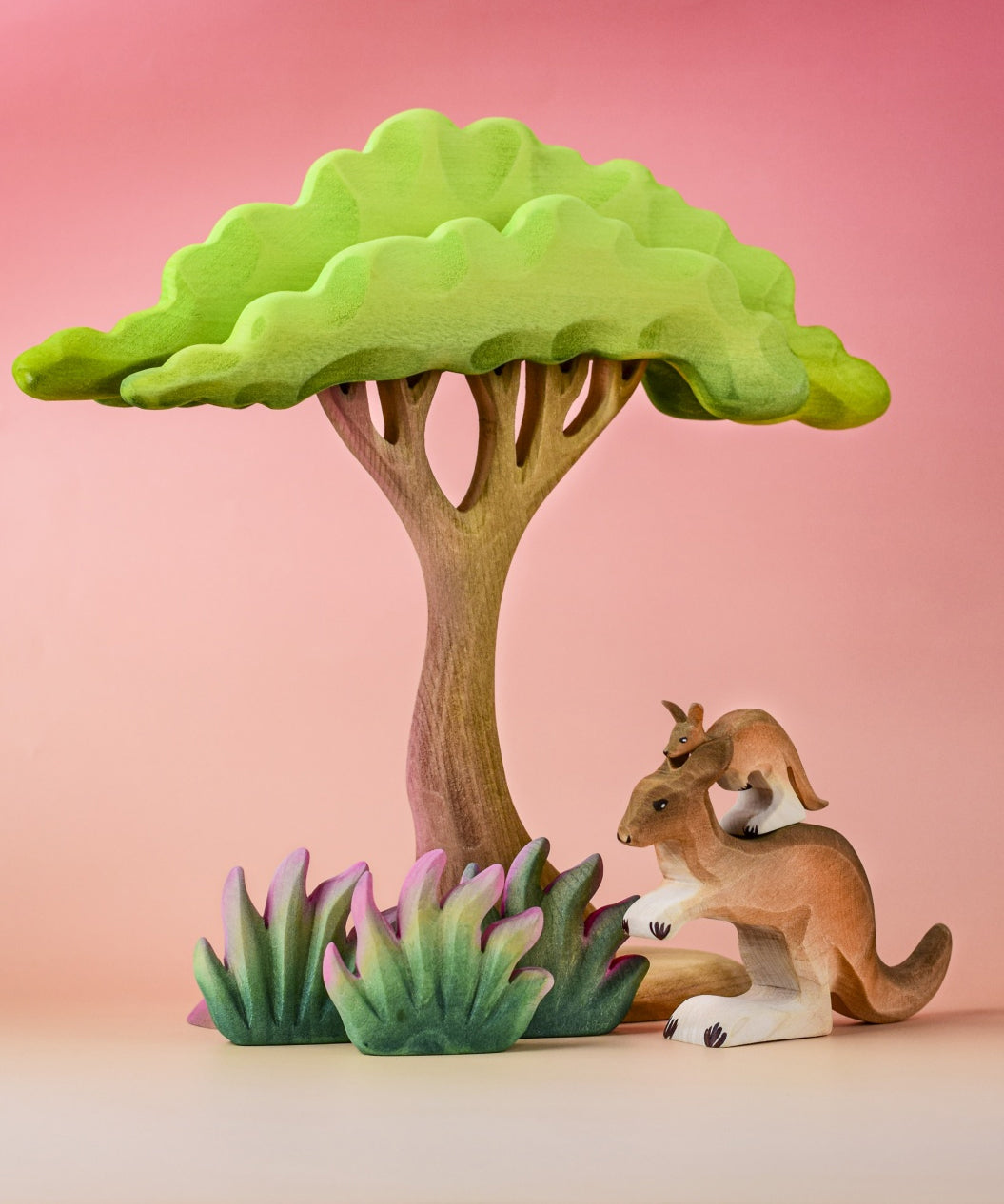 The Bumbu Toys Kangaroo in a small world play scene alongside wooden grass and trees.