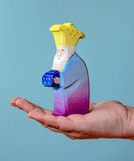 Bumbu Wooden Nativity Figure - Three Kings Melchior on an adults hand with blue background.