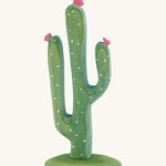 Green Bumbu cactus with pink flowers on a cream background