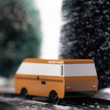 CandyLab VW T3 Campervan in brown - back view, driving down a snowy road in the forest.