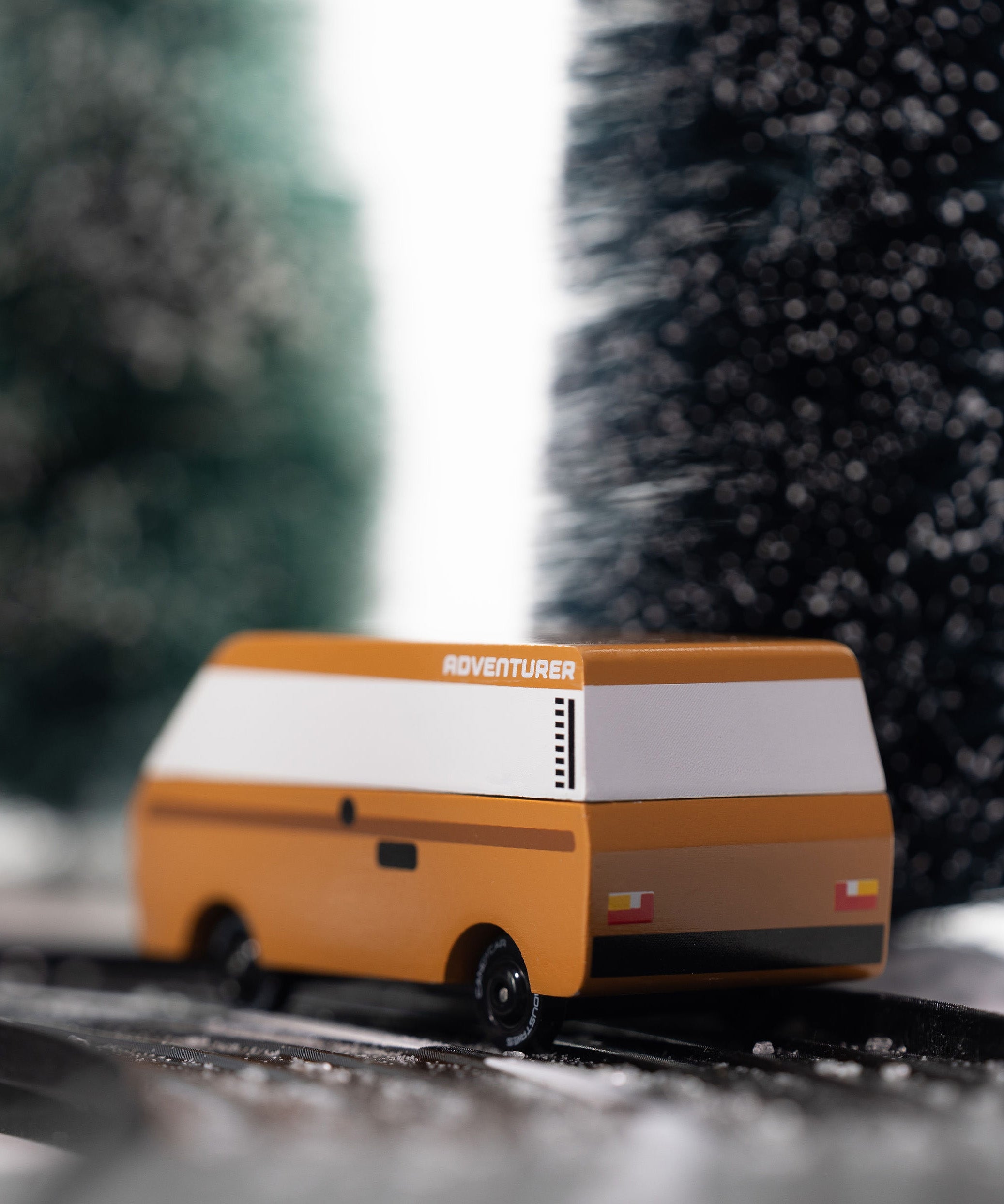 CandyLab VW T3 Campervan in brown - back view, driving down a snowy road in the forest.