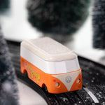 Front view of CandyLab orange VW T1 Campervan with 'Groovy' text on the side in a 60s font - driving through a snowy forest. 