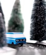 CandyLab blue VW T3 CandyVan with white stripe on the side - front view on a road through a wintry forest.
