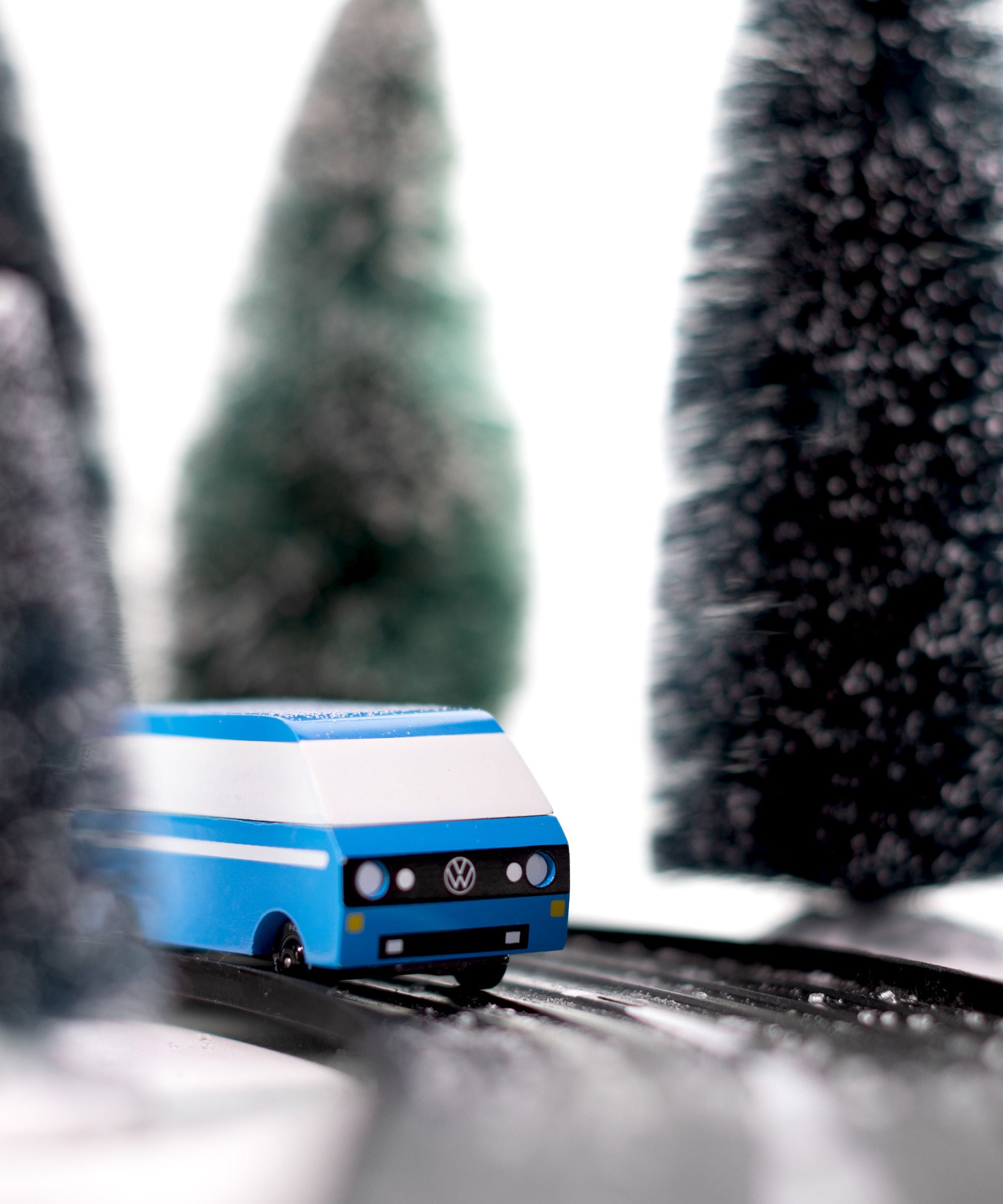 CandyLab blue VW T3 CandyVan with white stripe on the side - front view on a road through a wintry forest.