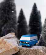 CandyLab blue VW T3 CandyVan with white stripe on the side - front view parked on rocks in a snowy forest.