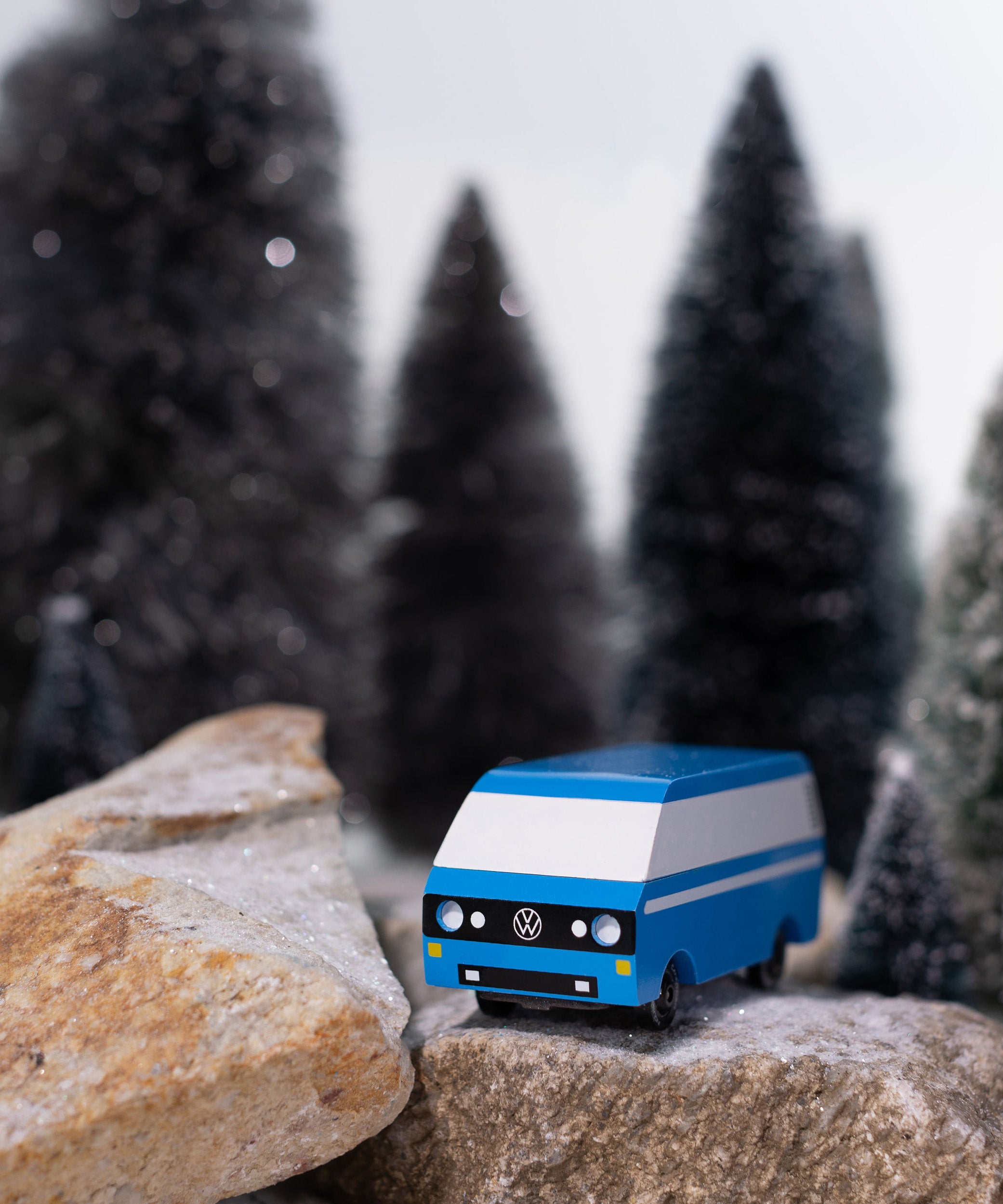 CandyLab blue VW T3 CandyVan with white stripe on the side - front view parked on rocks in a snowy forest.