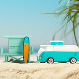 Candylab blue wooden beach van toy on some yellow sand in front of a palm tree