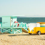 Candylab solid wooden campervan toy on a sandy beach next to a wooden beach hut toy