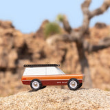 Candylab solid wooden vehicle toy on a large rock in front of a tree