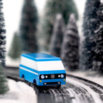 CandyLab blue VW T3 CandyVan with white stripe on the side - front view on a road through a wintry forest.