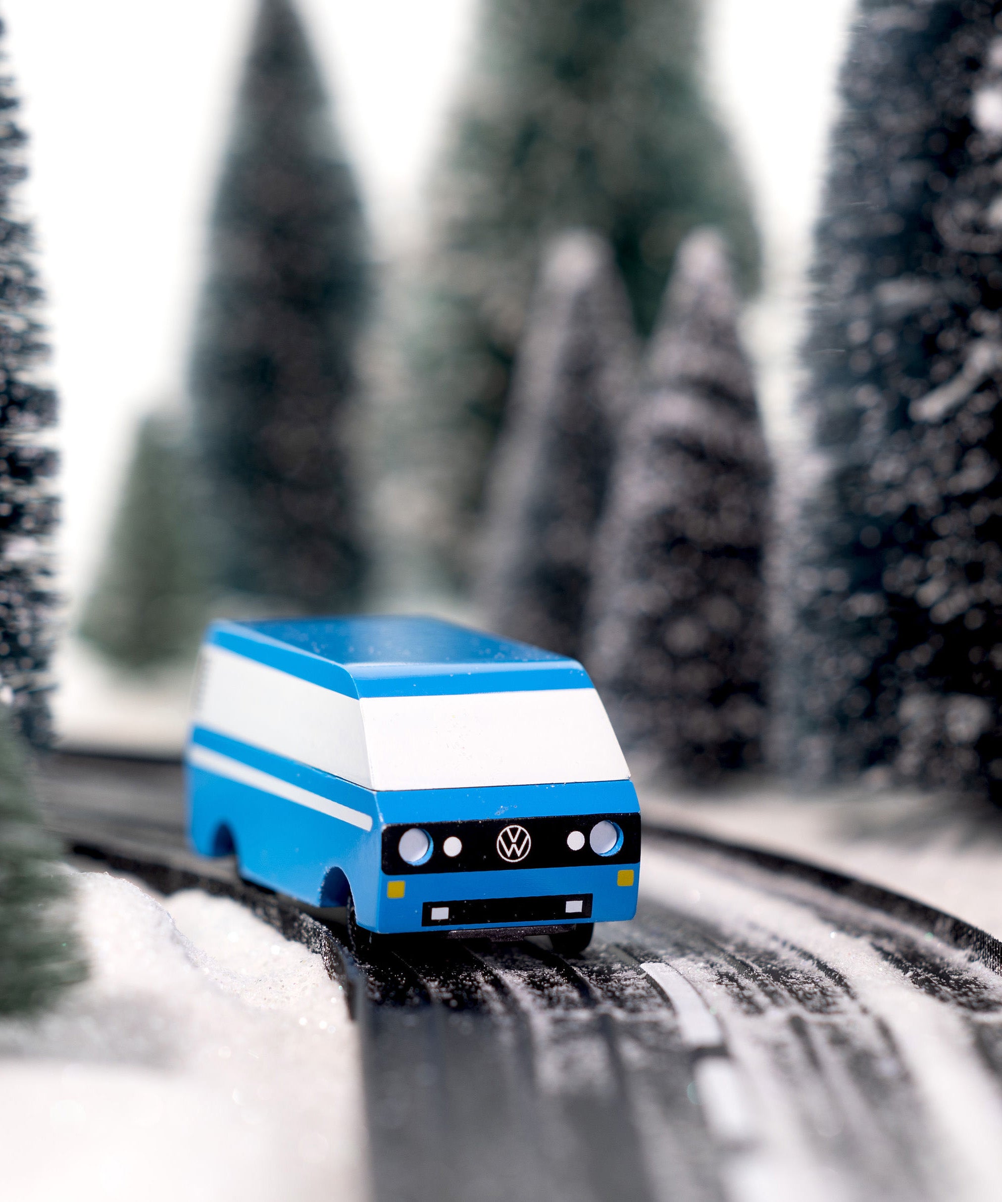 CandyLab blue VW T3 CandyVan with white stripe on the side - front view on a road through a wintry forest.