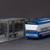 Candylab handmade wooden diecast bus toy on a grey background next to a miniature bus stop