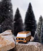 CandyLab Volkswagen T3 Campervan in brown - front view, on a rock in a snowy forest environment. 