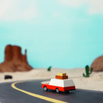 Candylab wooden luggage wagon collectable car toy on a rubber road in front of a rocky landscape