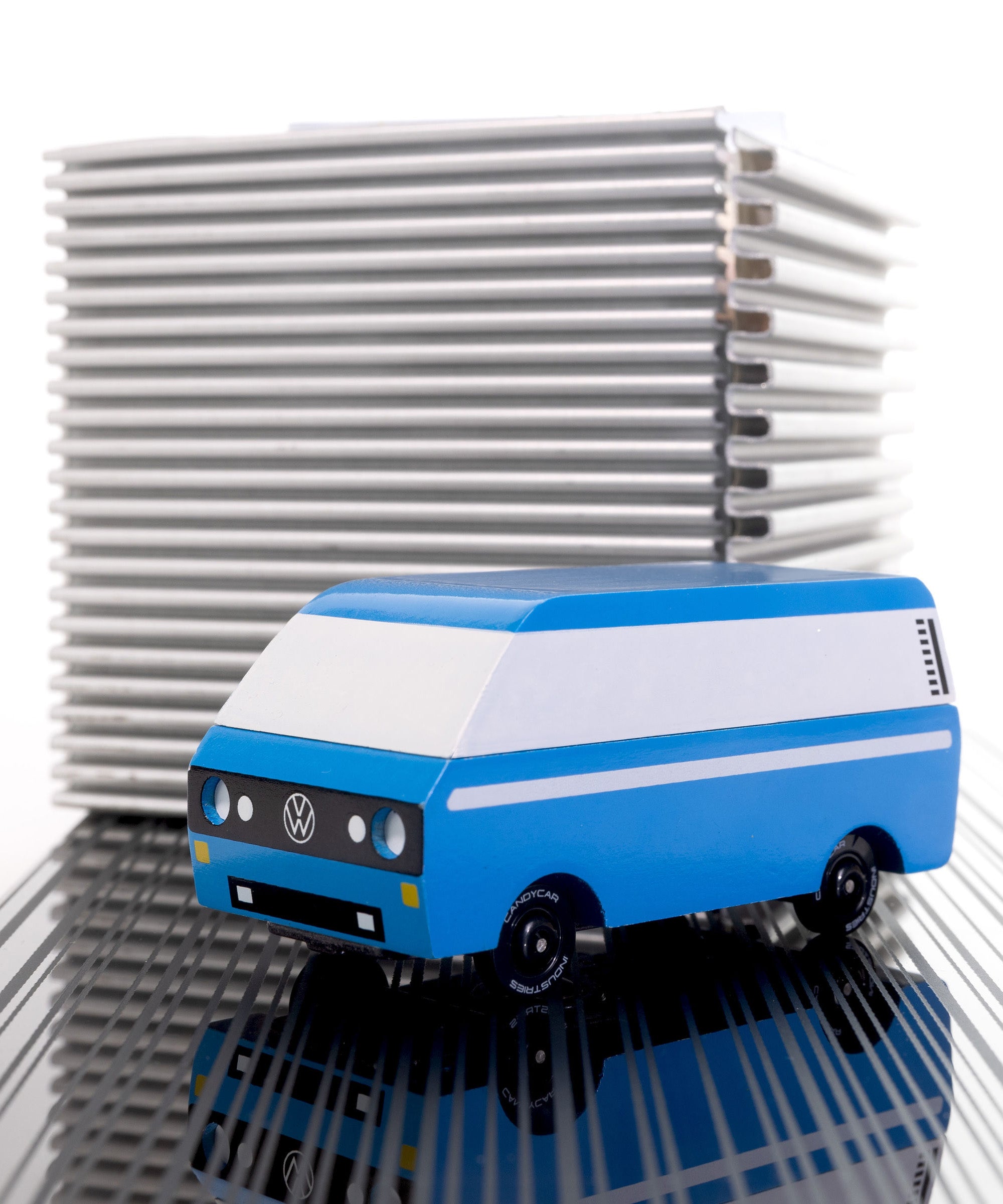 CandyLab blue VW T3 CandyVan with white stripe on the side - parked in front to a metal cube.