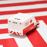 Candylab childrens small wooden ambulance toy on a red and white striped background
