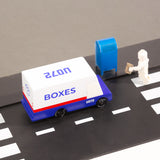 Close up of a Candylab wooden post van next to a toy mailbox and toy figure on a black rubber road