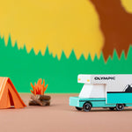 Candylab collectable diecast rv toy next to a paper tent in front of a yellow mountain background