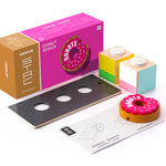 Pieces of the plastic-free Candylab donut shack collectable set on a white background next to the pink box