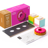 Pieces of the plastic-free Candylab donut shack collectable set on a white background next to the pink box