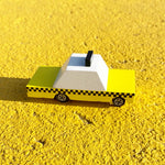 Close up of the Candylab handmade wooden taxi toy car on a yellow floor