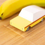 Close up of the Candylab wooden banana car toy on a wooden table next to a banana