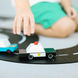 Close up of a childs hand pushing the candylab handmade wooden police car on a black rubber road