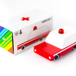 Candylab wooden ambulance toy on a white background next to its cardboard box