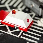 Close up of the Candylab solid wooden ambulance toy car on a black rubber road