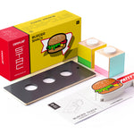 Pieces of the Candylab slotting wooden burger shack on a white background next to its cardboard box