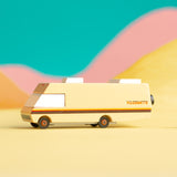 Candylab childrens diecast wooden campervan toy on a yellow background in front of some orange and pink hills
