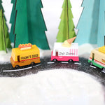 3 Candylab handmade wooden toy trucks driving on a toy road in a snowy Winter scene