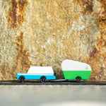 Candylab blue wooden suv toy towing a small green caravan toy in front of a stone background