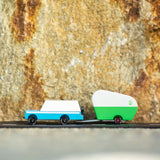 Candylab blue wooden suv toy towing a small green caravan toy in front of a stone background