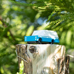 Candylab solid wooden suv toy vehicle on a tree stump in front of some green leaves