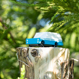 Candylab solid wooden suv toy vehicle on a tree stump in front of some green leaves