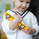 Close up of a young boy in a white jumper holding a Candylab solid wooden taxi cab diecast car toy