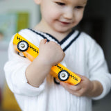 Close up of a young boy in a white jumper holding a Candylab solid wooden taxi cab diecast car toy