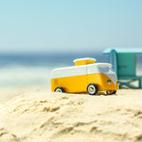Close up of a wooden Candylab vw campervan toy on a sandy beach in front of a blue sky