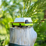 Candylab eco-friendly collectable wooden suv toy on a wooden post in front of some green leaves