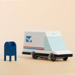 Candylab collectable wooden mail van toy on a beige background next to a miniature blue postbox