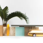 Candylab childrens wooden diecast car toy in front of a small wooden shack model and palm tree